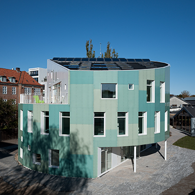 Round building with green tinted facade and many windows and skylights