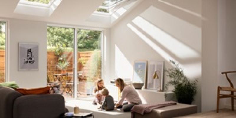 A mother and her kids are playing on the floor in the living room enjoying the daylight from their VELUX roof windows
