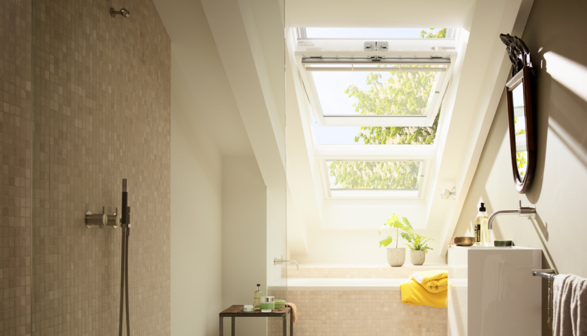Bright and modern bathroom with a large VELUX roof window overlooking the bathtub.