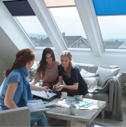 Three woman talking about the VELUX blind decoration for their three VELUX roof windows behind them.