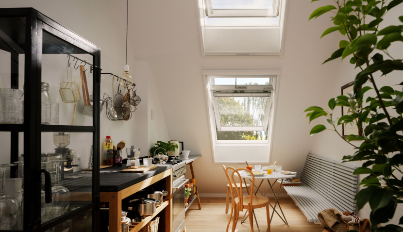 Cozy, open kitchen with a small kitchen table and two VELUX roof windows installed in the roof.