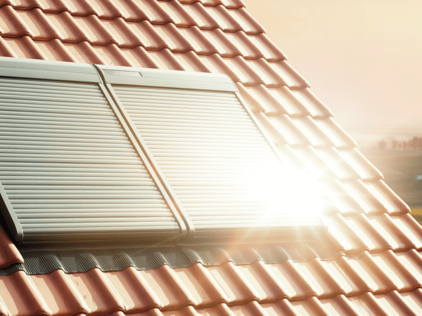 Exterior shutters installed in red roof tiles with sun hitting the surface