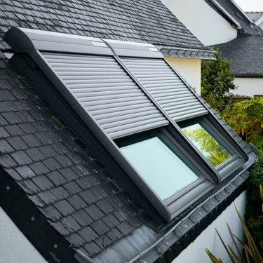 Two black external VELUX roller shutters are attached to two VELUX roof windows.